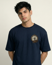 Man wearing a Toneos navy blue t-shirt with a compass design on a beige background